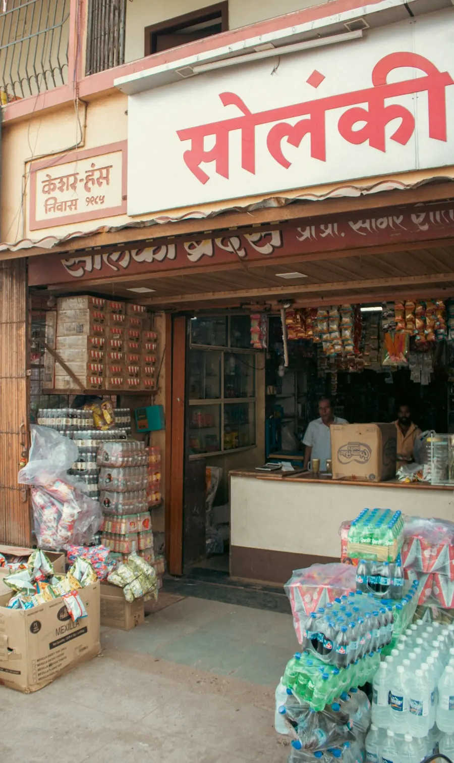 A family-run general store with a Devanagari signboard and stacked goods out front.